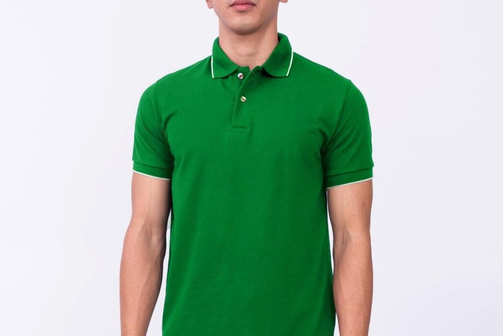Man wearing a green plain polo shirt with white piping on the collar and sleeves against a light background