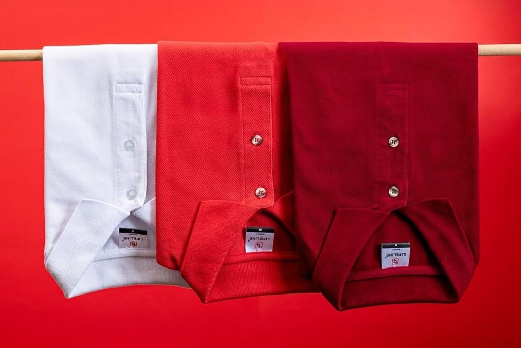 White, red, and maroon Lifeline polo shirts folded on a red background