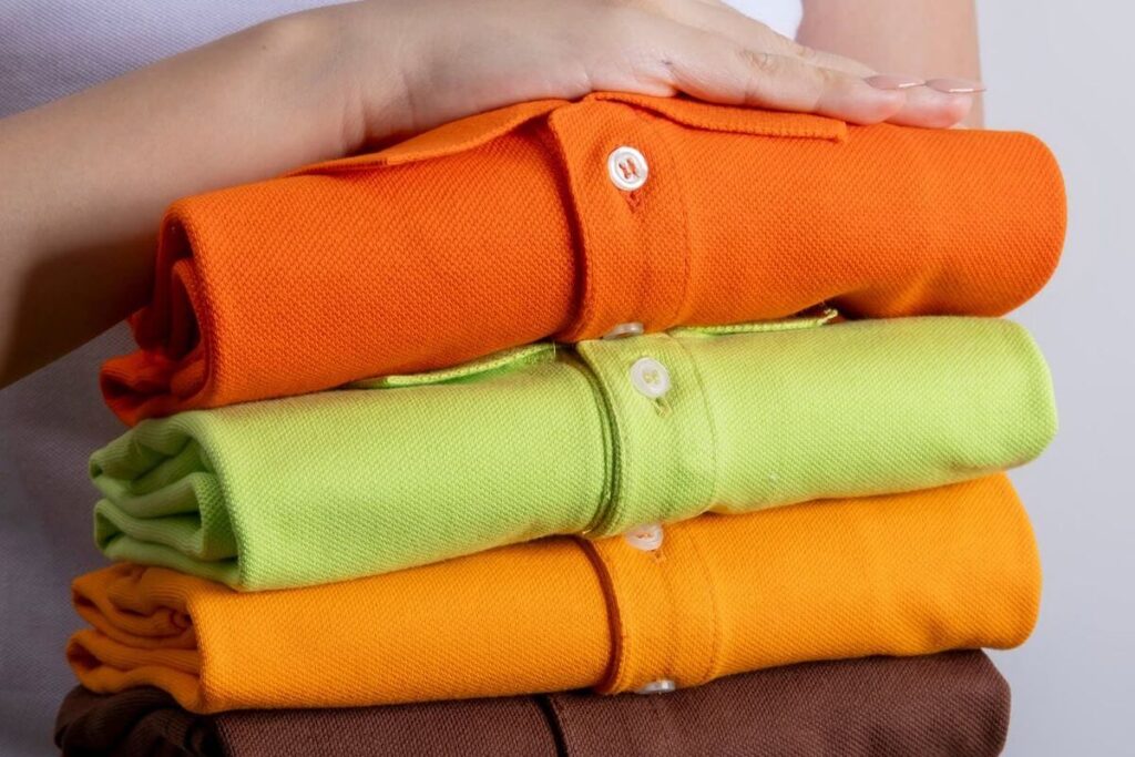 Stack of folded Lifeline polo shirts in orange, green, yellow, and brown