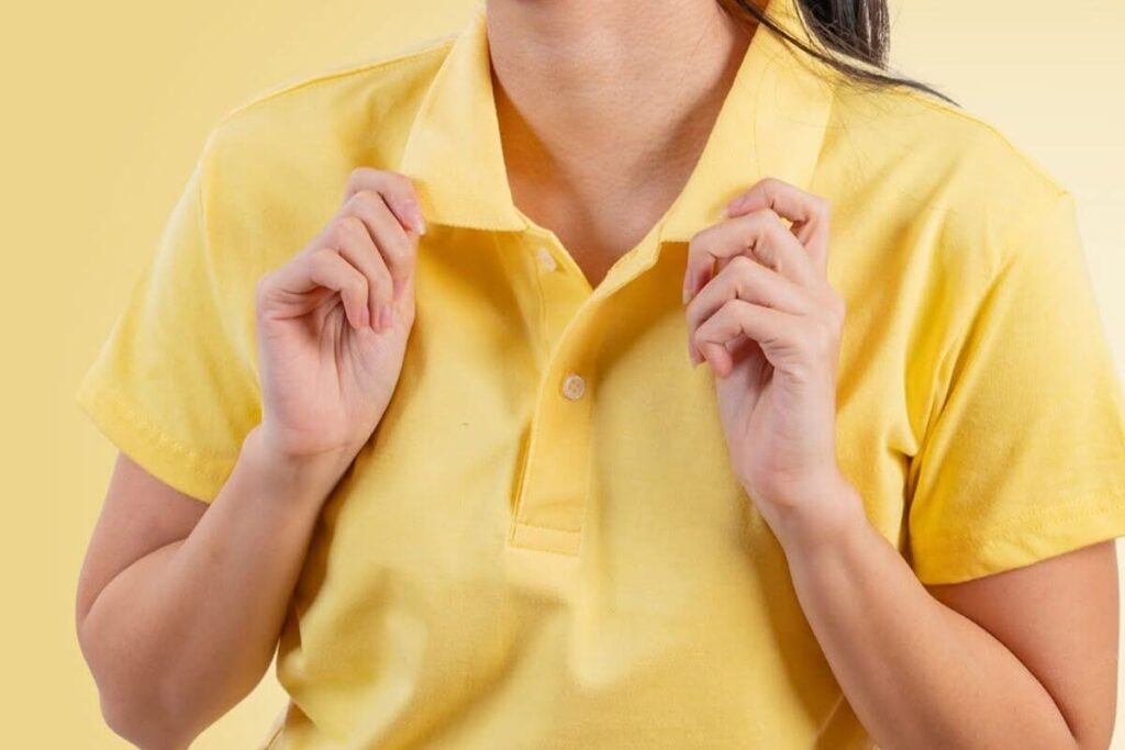 Female model adjusting the collar of a yellow polo shirt