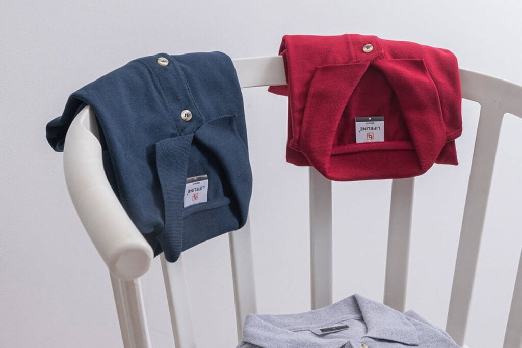 Navy, red, and gray Lifeline polo shirts displayed on a white chair