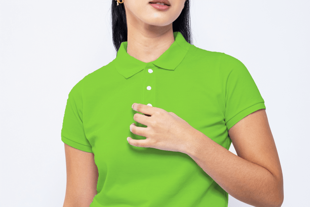 Female model wearing a bright green polo shirt while lightly adjusting the fabric near the chest