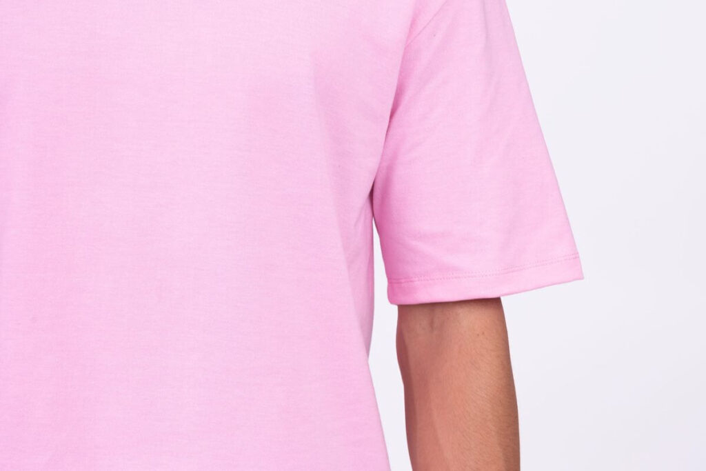 Close-up of a pink plain round neck shirt showing smooth fabric texture, stitching, and sleeve fit